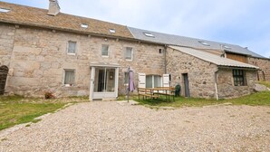 A stone building with a gravel driveway, a wooden bench, and a door with glass panels. - Gîte La Parro - MALBOUZON (MALBOUZON)