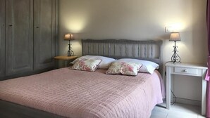 A bedroom with a large bed, two bedside tables with lamps, a wardrobe, and a small white desk. - Gîte La Parro - MALBOUZON (MALBOUZON)