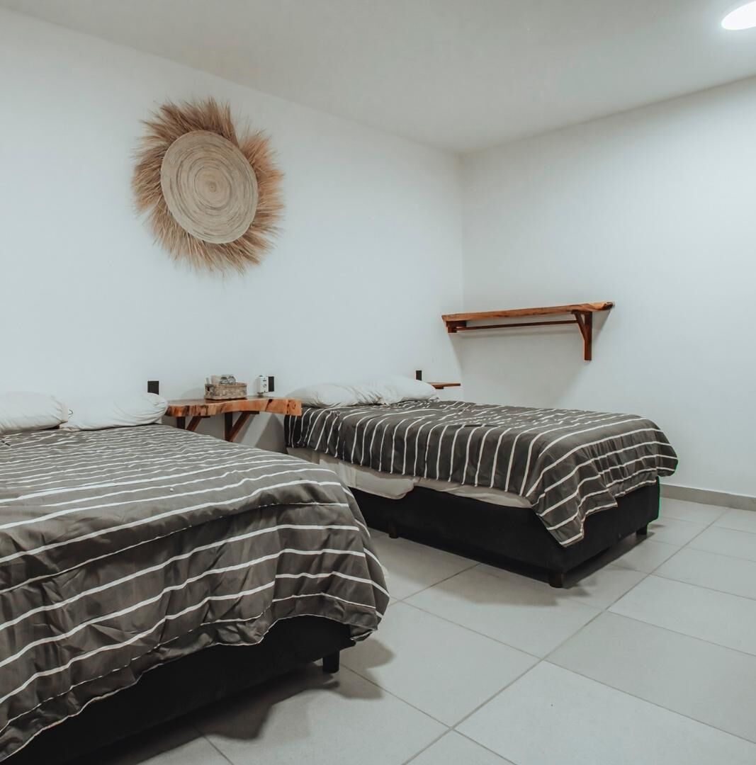 A room with two beds, a wall-mounted shelf, and a decorative wall piece.