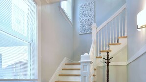 A staircase with wooden steps and white railings, leading to an upper floor.