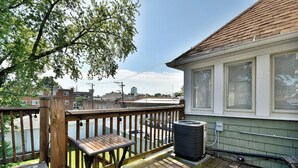 A wooden deck with a table and an air conditioning unit.
