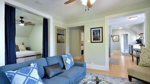 A living room with a blue sofa, a glass coffee table, and a ceiling fan.