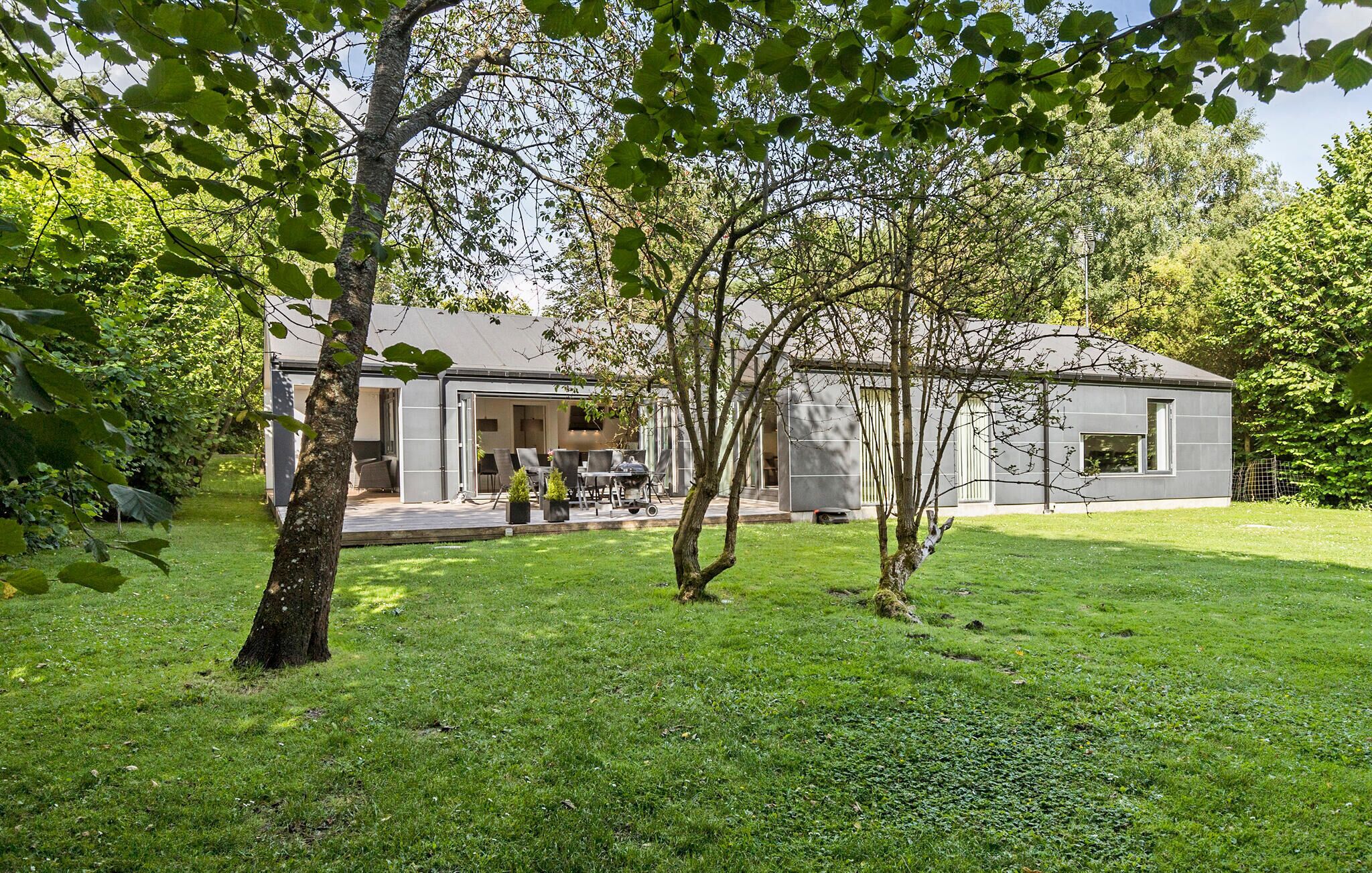 A modern house with a patio, a barbecue, and a small garden area.