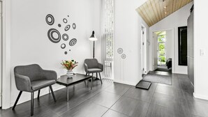 A modern interior with two grey armchairs, a small table with a vase, and a floor lamp.
