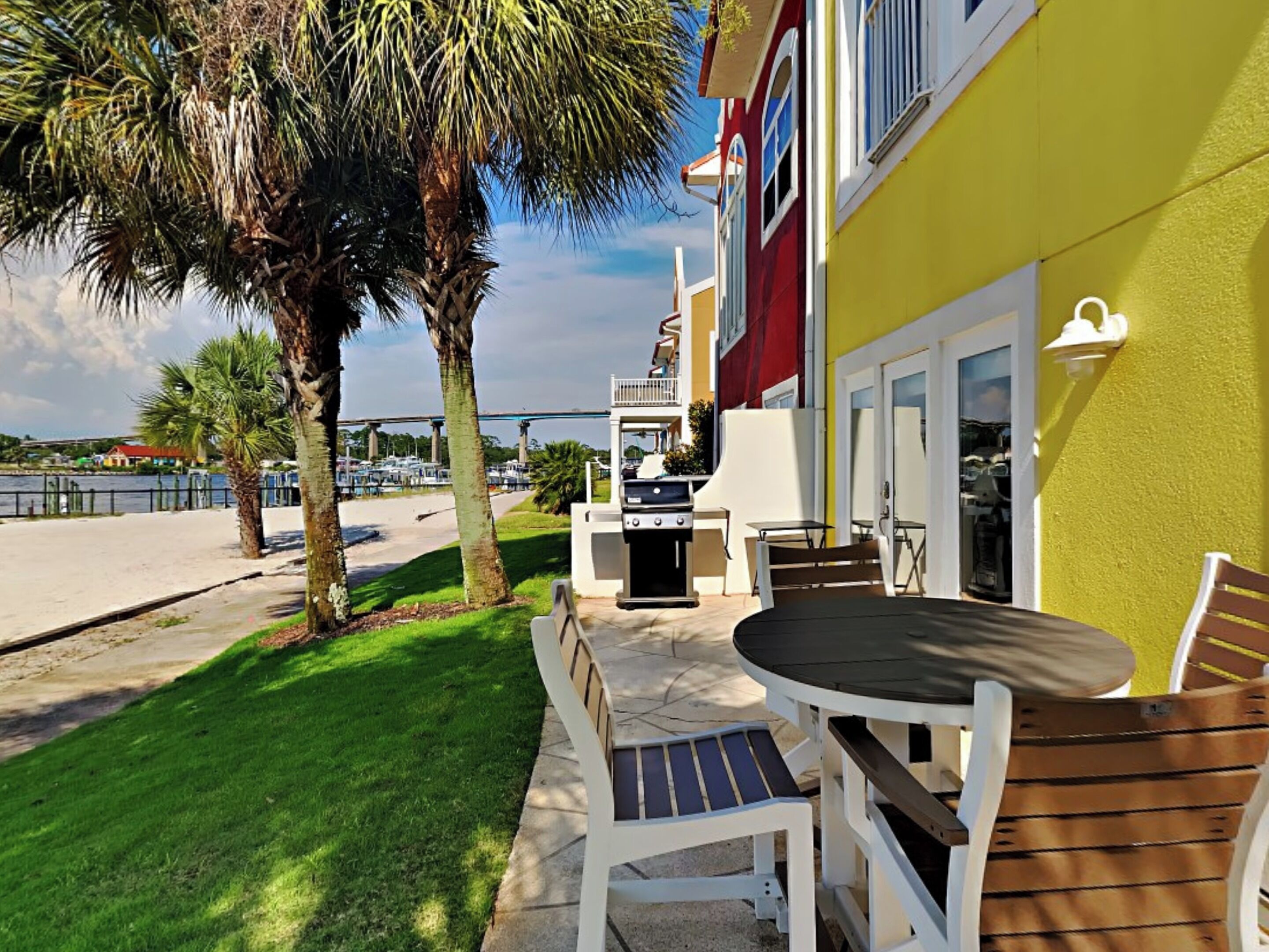 A patio with a table and chairs, a grill, and a view of a marina.