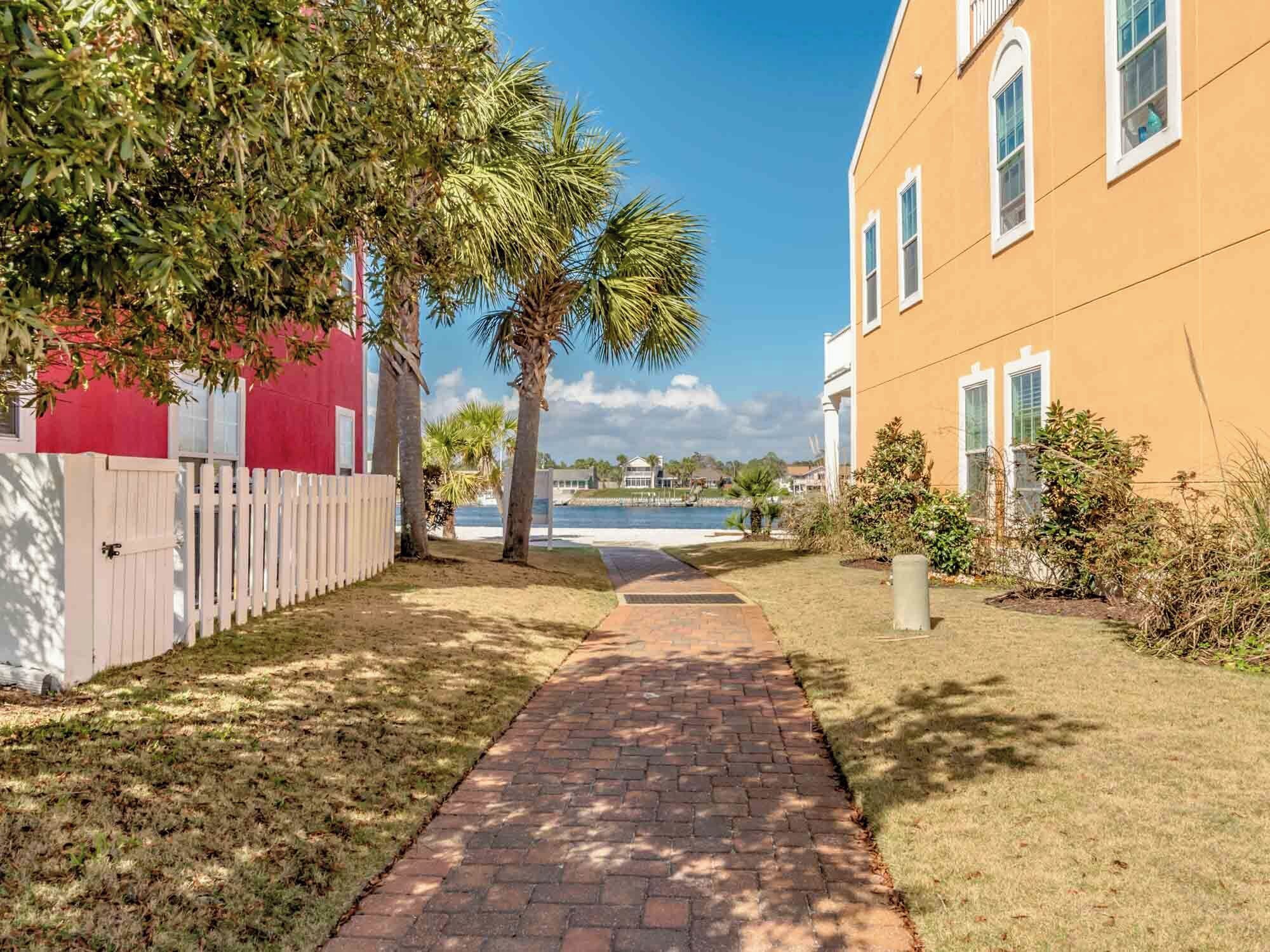 A pathway leading to a building with a red fence and palm trees.