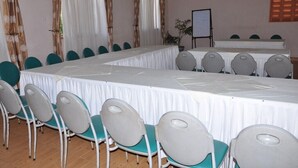 A conference room with a long table, teal chairs, white drapes, and a whiteboard. - City Side Hotels and Apartments Mukono (Mukono)