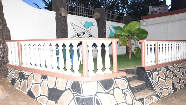 A stone wall with a decorative railing, a palm tree, and a sign for Deira Hotel Ltd. - City Side Hotels and Apartments Mukono (Mukono)
