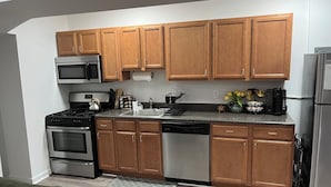 A modern kitchen with wooden cabinets, stainless steel appliances, and a granite countertop.