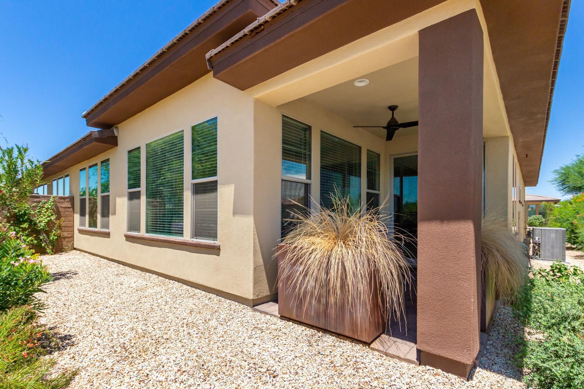 A modern house with a covered porch, large windows, and a decorative plant in the entrance.