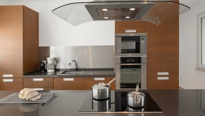 A modern kitchen with a central island, stainless steel appliances, and wooden cabinetry. - Poolside and Seaview Villa (Lisboa)