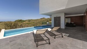 A modern outdoor pool area with a clear view of the landscape, a covered seating area, and a contemporary design. - Poolside and Seaview Villa (Lisboa)