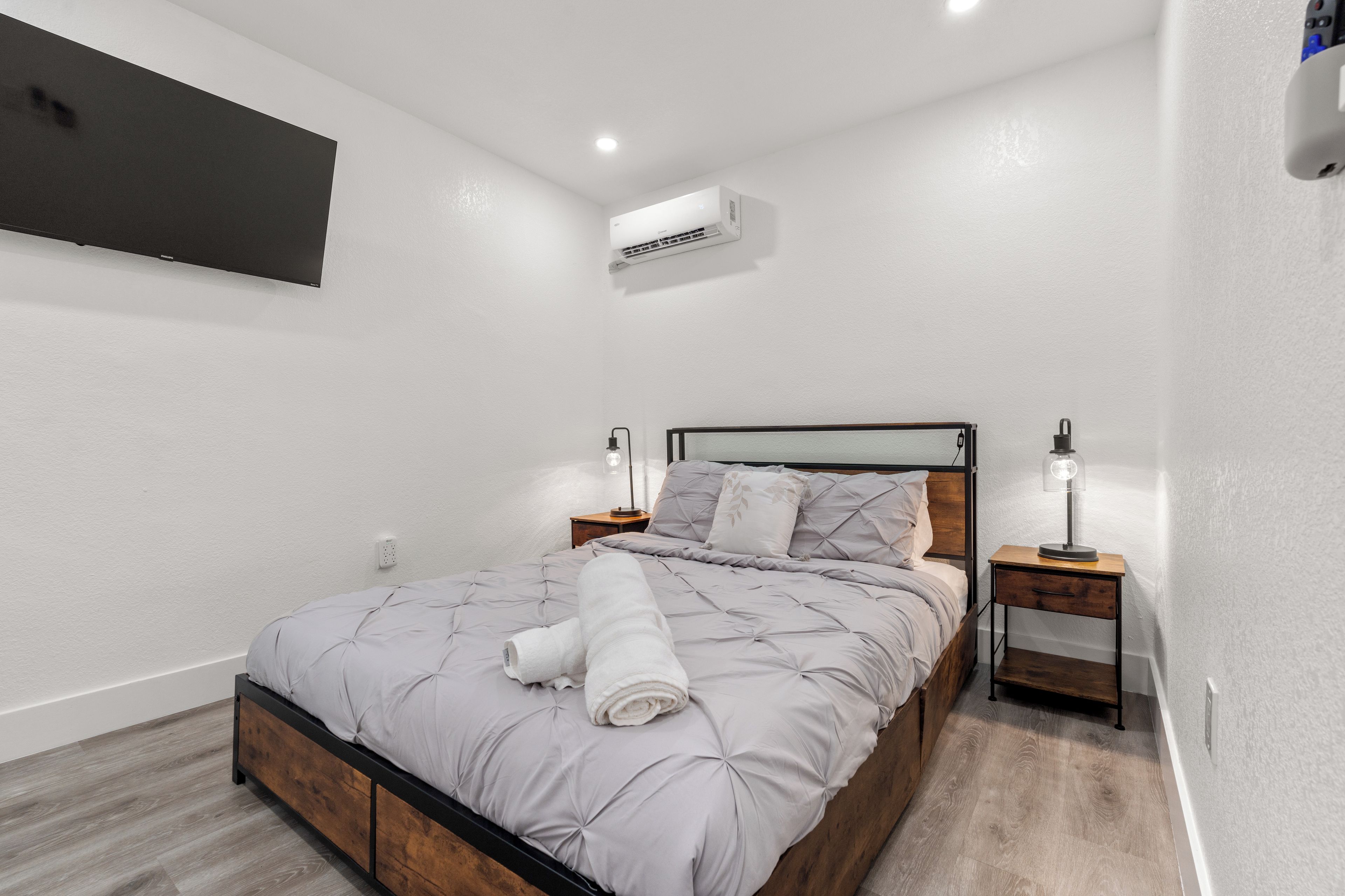 Un dormitorio moderno con cama, lámparas de noche y un equipo de aire acondicionado.