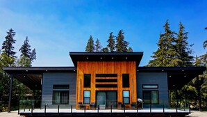 Un bâtiment moderne doté d’une façade en bois, de grandes fenêtres et d’un espace d’entrée abrité.