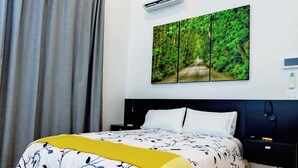 Une chambre à coucher comprenant un lit, une table de chevet, un appareil de climatisation et un tableau accroché au mur.