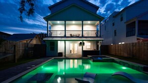 Une maison à deux étages dotée d’une piscine, d’un patio couvert et d’une cuisine ouverte.