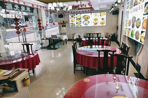 Interior de un restaurante con mesas redondas, sillas y un panel con el menú.
