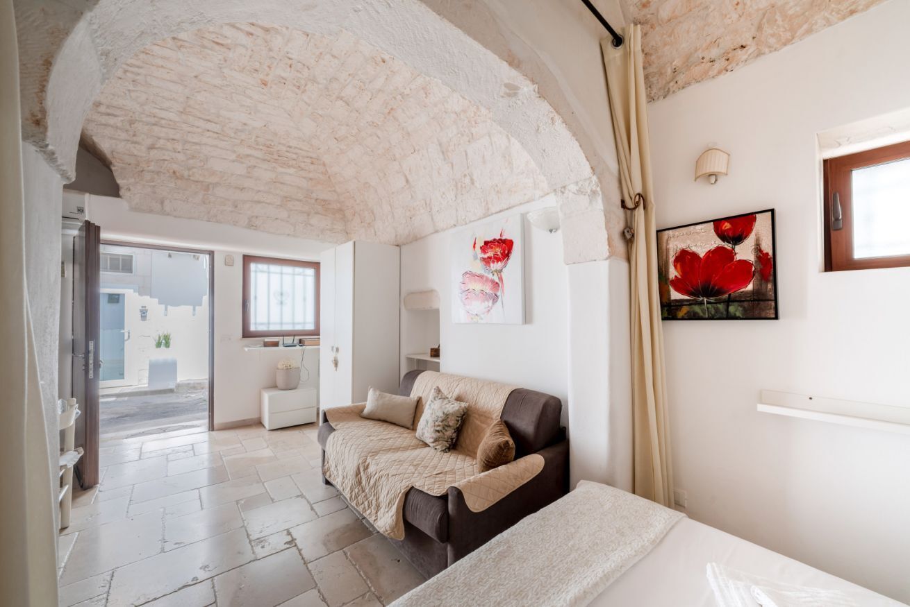 Une pièce avec un plafond en pierre, un canapé, un lit et deux tableaux accrochés au mur.