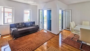 A modern living room with a sofa, a coffee table, and a dining area with a table and chairs. - Gorgeous apartment in Novi Vinodolski with WiFi (Novi Vinodolski)
