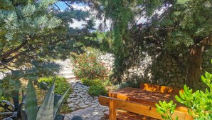 A stone pathway leading to a wooden bench surrounded by lush greenery and a stone wall. - Gorgeous apartment in Novi Vinodolski with WiFi (Novi Vinodolski)