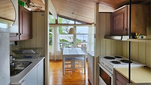 Una cocina compacta con armarios de madera, estufa y zona de comedor con mesa y sillas.