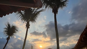 A sunset view from a terrace with palm trees, a pool, and a boat dock. - Pousada Jet Club Marine Angra (Angra dos Reis)