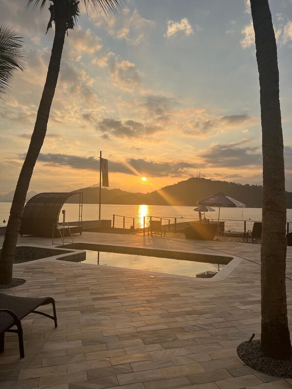 Una piscina al aire libre, sombrillas, sillones reclinables de piscina