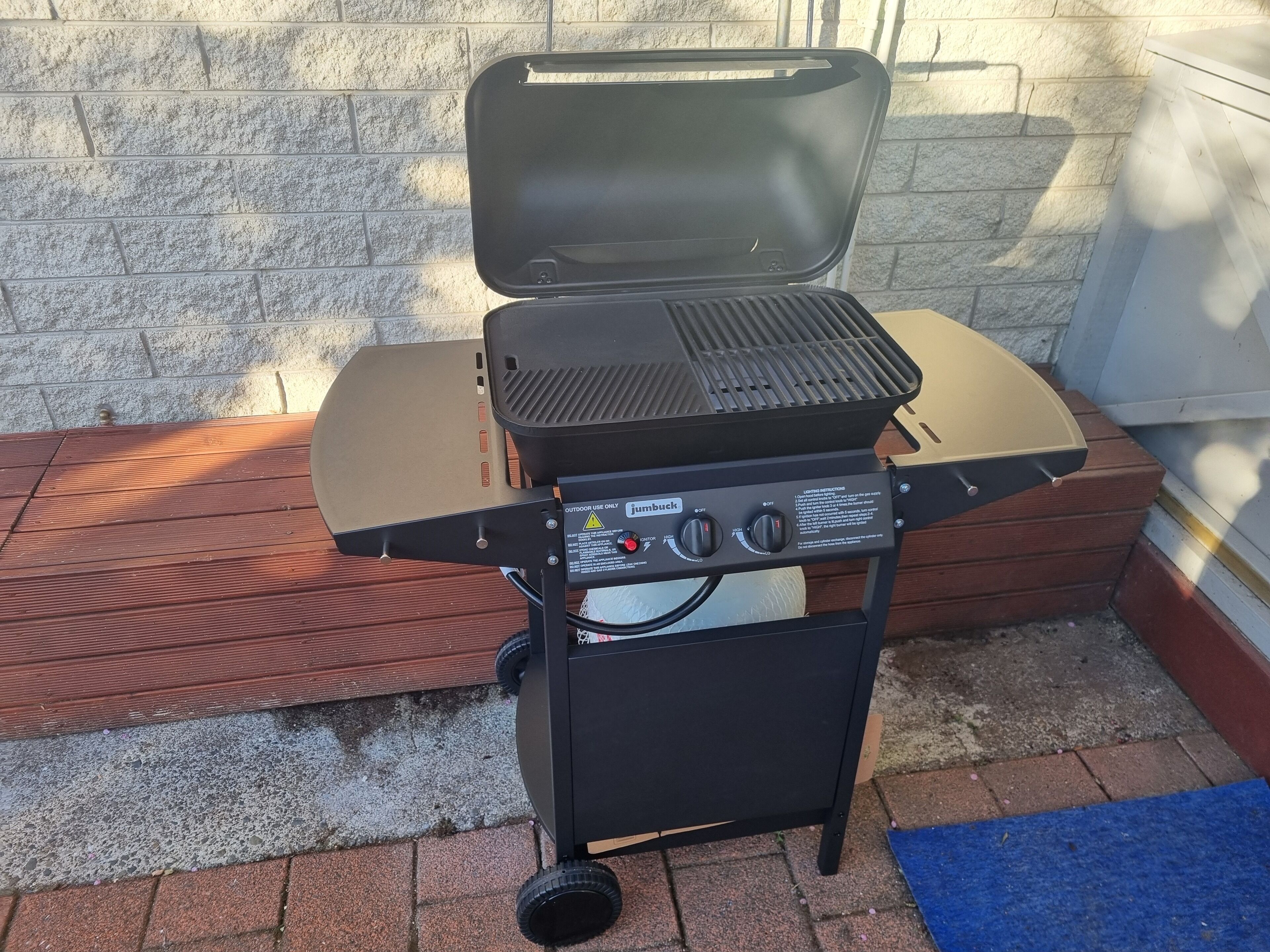 A portable grill with a control panel, set against a stone wall.