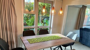 A dining area with a wooden table, black chairs, and a bench. There are two pendant lights above the table. - Home with spa, sauna, garden in prime location (Rotorua)
