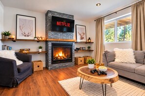 Una sala de estar acogedora con chimenea, una pantalla de Netflix y un espacio de descanso cómodo.