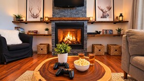 A cozy living room with a fireplace, a gaming setup, and a comfortable seating area.