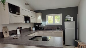 A modern kitchen with white cabinets, a built-in stove, a microwave, and a refrigerator. - House with covered swimming pool and pétanque court (Lanchéres)
