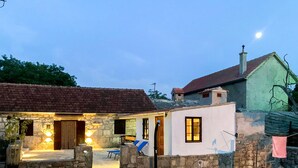 Una casa de piedra con techo de tejas, un pequeño porche y un interior bien iluminado.