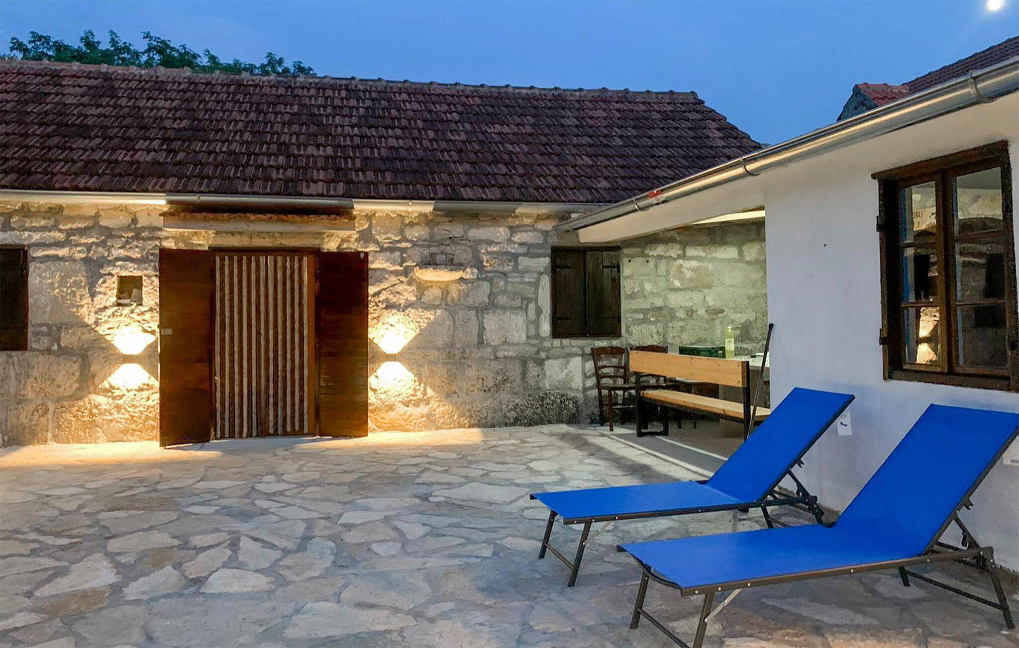 Ein Gebäude aus Stein mit einem Ziegeldach, einer Holztür und zwei blauen Lounge-Stühlen.
