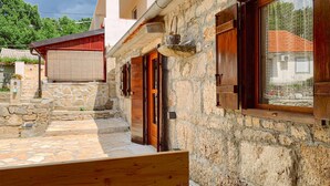 Un edificio de piedra con contraventanas de madera y un pequeño porche.