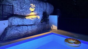 Una piscina con una formación rocosa y una lámpara.