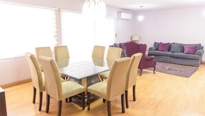 A dining area with a glass table and wicker chairs, a grey sofa with cushions, and a chandelier. - New Cozy San Pedro Home Patio Work Area (San Pedro Garza García)
