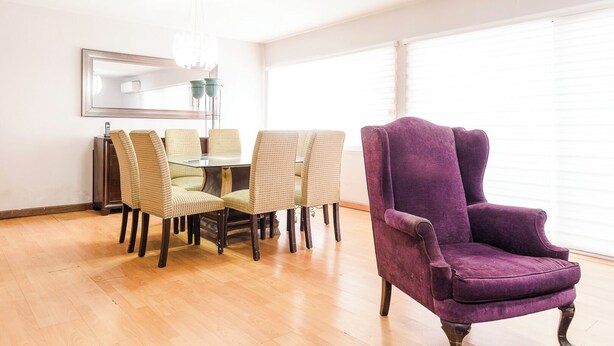 A dining area with a round table and six chairs, a purple armchair, a mirror on the wall, and a chandelier. - New Cozy San Pedro Home Patio Work Area (San Pedro Garza García)