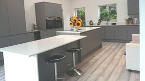 Una cocina moderna con una isla central, taburetes de bar y un tragaluz.