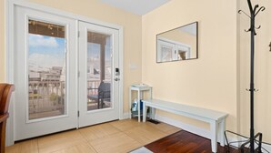 A room with a sliding glass door, a bench, a coat rack, and a small table with a chair. - Bay view-walk to beach/boards/restaurants, parking (Ventnor City)