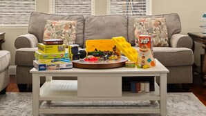 A living room with a white coffee table, a sofa, and various children's toys and books. - Bay view-walk to beach/boards/restaurants, parking (Ventnor City)