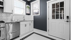 Una cucina moderna con mobili bianchi, una lavastoviglie in acciaio inossidabile e uno schienale piastrellato.