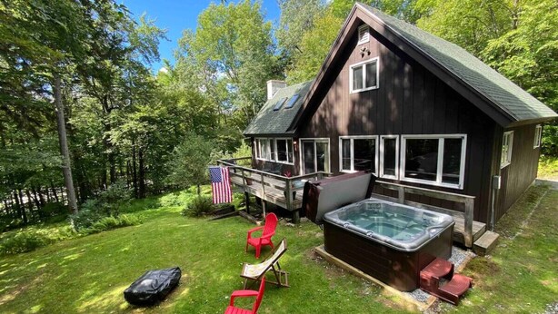 Une cabane avec un jacuzzi, des chaises longues et un drapeau américain.