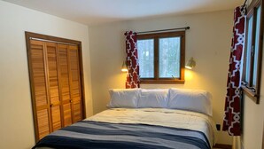 Une chambre à coucher avec un lit, une fenêtre avec des rideaux et une armoire.