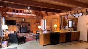 Un intérieur de chalet chaleureux comprenant un coin repas, une cuisine et une cheminée.