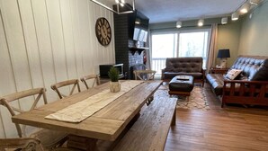 Un salon spacieux avec une table à manger en bois, des canapés en cuir et une cheminée.