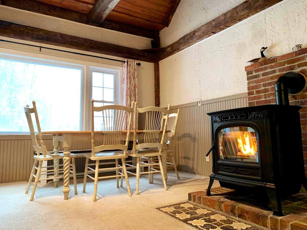 Ein Zimmer mit Kamin aus Backstein, Holzstühlen und einem Tisch.