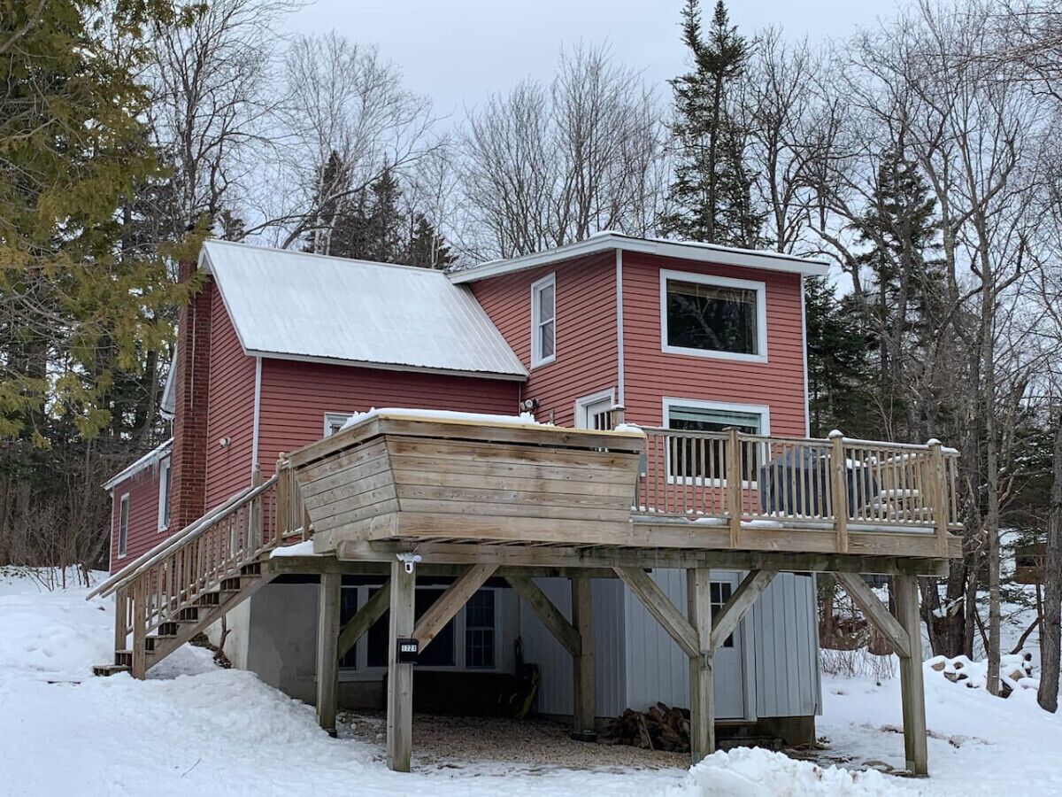 A red wooden house with a deck and a covered porch.