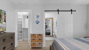 Een slaapkamer met een bed, een dressoir, een kledingkast en een schuifdeur in boerderijstijl.