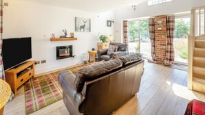 A spacious living room with a fireplace, a television, and a comfortable sofa. - 1 bedroom accommodation in Pickering (Pickering)